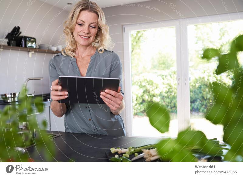 Lächelnde Frau benutzt Tablette in der Küche lächeln Tablet Computer Tablet-PC Tablet PC iPad Tablet-Computer Küchen weiblich Frauen Rechner Erwachsener