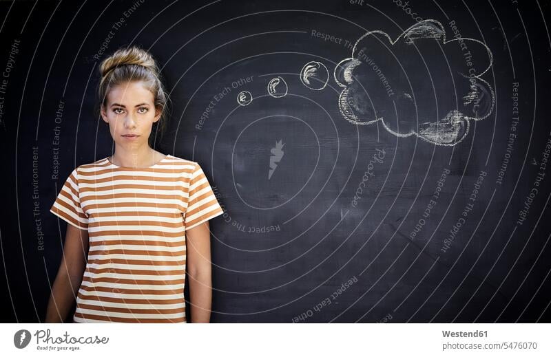 Nachdenkliche junge Frau, die vor einer Tafel neben einer Gedankenblase steht Schultafel Schultafeln T-Shirts stehend Kreativ Lifestyles Attraktivität