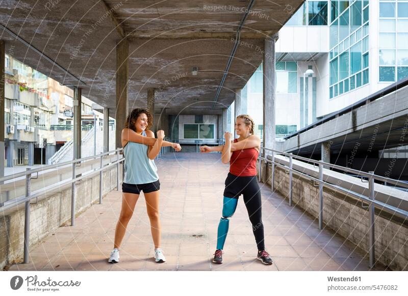 Sportlerin mit Beinprothese trainiert mit Freund auf einer Brücke stehend Farbaufnahme Farbe Farbfoto Farbphoto Außenaufnahme außen draußen im Freien Tag