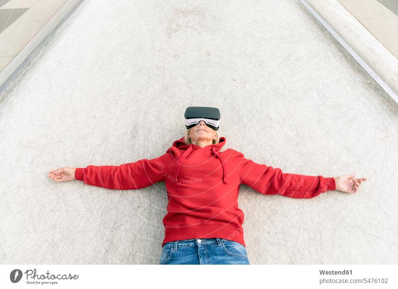 Ältere Frau mit VR-Brille auf dem Boden liegend Brillen liegt Grund Land virtuell Virtualität weiblich Frauen Erwachsener erwachsen Mensch Menschen Leute People