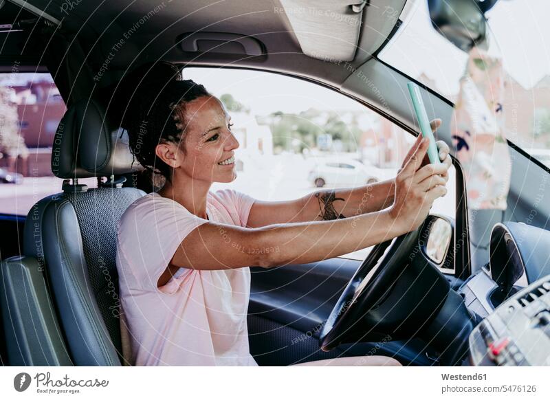 Lächelnde Frau, die ein Selfie macht, während sie an einem sonnigen Tag im Auto sitzt Farbaufnahme Farbe Farbfoto Farbphoto Spanien Tageslichtaufnahme