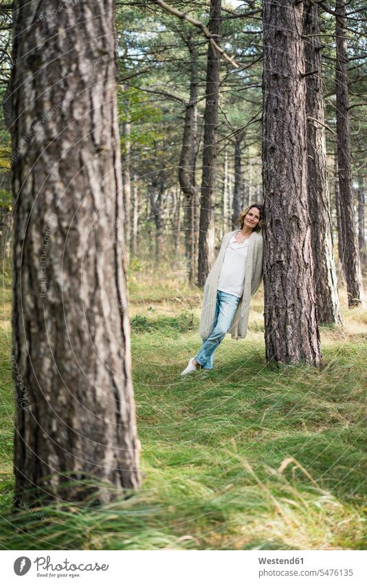 Serene Frau steht im Wald Entspannung relaxen entspannen Baumstamm Stamm Stämme Baumstämme Auszeit Alles hinter sich lassen abschalten Forst Wälder reife Frau