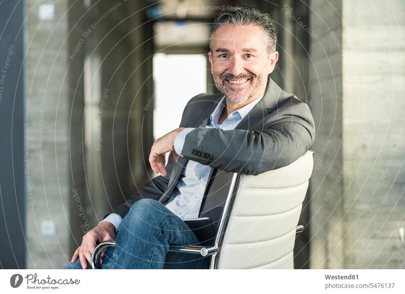 Porträt eines lächelnden reifen Geschäftsmannes, der auf einem Stuhl im Büro sitzt Job Berufe Berufstätigkeit Beschäftigung Jobs geschäftlich Geschäftsleben