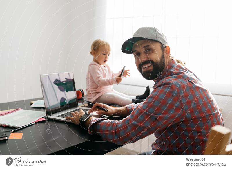 Vater arbeitet von zu Hause aus, mit Laptop mit seiner Tochter sitzt auf dem Schreibtisch, spielen Zuhause arbeiten von zuhause arbeiten