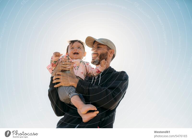 Lachender Vater hält kleines Mädchen im Gegenlicht weibliche Babys weibliches Baby weibliche Babies Papas Väter Vati Vatis Papis lachen halten Säuglinge Kind