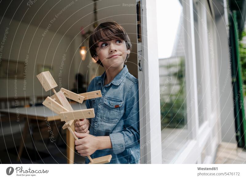 Kleiner Junge steht am Fenster und hält selbstgebauten Spielzeugroboter Leute Menschen People Person Personen Europäisch Kaukasier kaukasisch 1 Ein ein Mensch