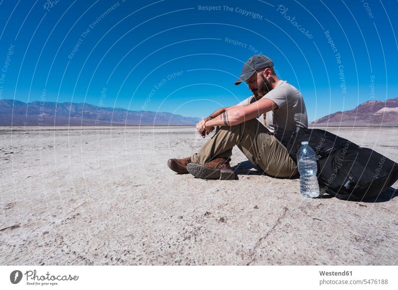 USA, Kalifornien, Death Valley, Mann sitzt auf dem Boden in der Wüste und ruht sich aus Männer männlich sitzen sitzend Wüsten Pause Grund Erwachsener erwachsen