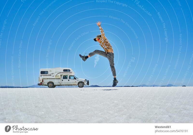 Bolivien, Salar de Uyuni, Junge springt auf Camper am Salzsee Wohnmobil Reisemobil Wohnmobile Wohnwagen Campingbus springen hüpfen Salzseen Buben Knabe Jungen