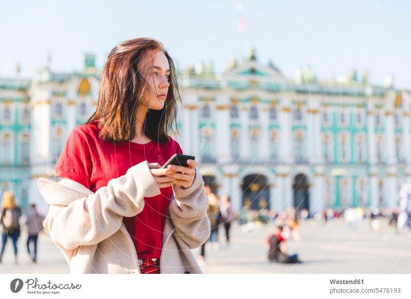Russland, St. Petersburg, junge Frau mit Smartphone in der Stadt Seitenblick Blick zur Seite Touristin Handy Mobiltelefon Handies Handys Mobiltelefone