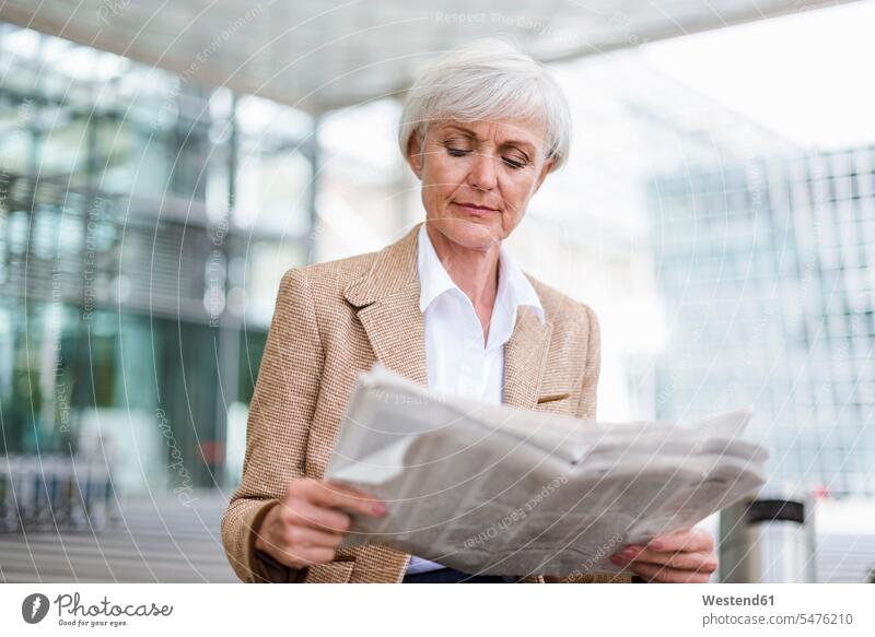 Ältere Geschäftsfrau in der Stadt liest Zeitung Zeitungen Seniorin älter Seniorinnen alt lesen Lektüre staedtisch städtisch Geschäftsfrauen Businesswomen