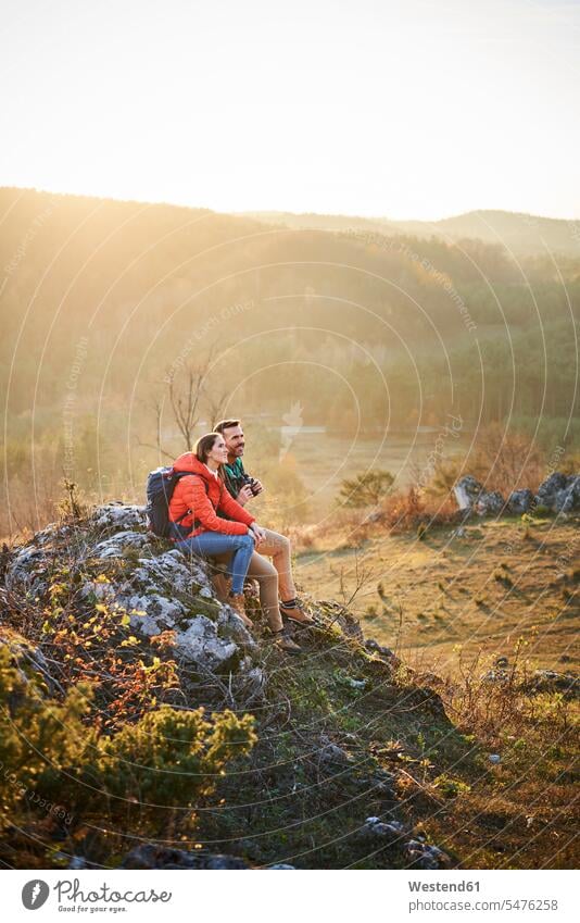Paar auf einer Wanderung in den Bergen mit einer Pause sitzen auf Felsen glücklich Glück glücklich sein glücklichsein Gebirge Berglandschaft Gebirgslandschaft