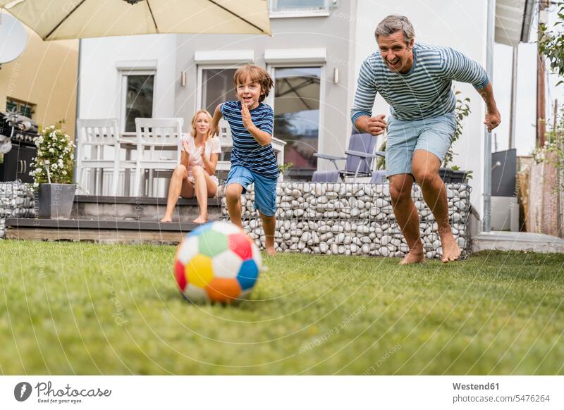 Vater und Sohn spielen im Garten Fussball Bälle Fußbälle rennen sommerlich Sommerzeit begeistert Enthusiasmus enthusiastisch Überschwang Überschwenglichkeit
