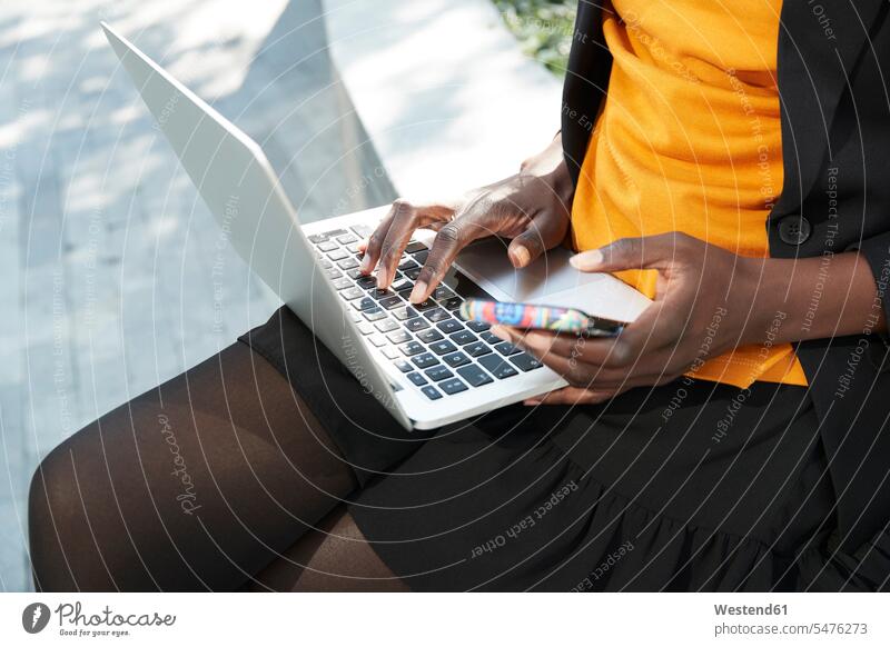 Weibliche Unternehmerin mit Mobiltelefon arbeitet am Laptop Farbaufnahme Farbe Farbfoto Farbphoto Außenaufnahme außen draußen im Freien Tag Tageslichtaufnahme