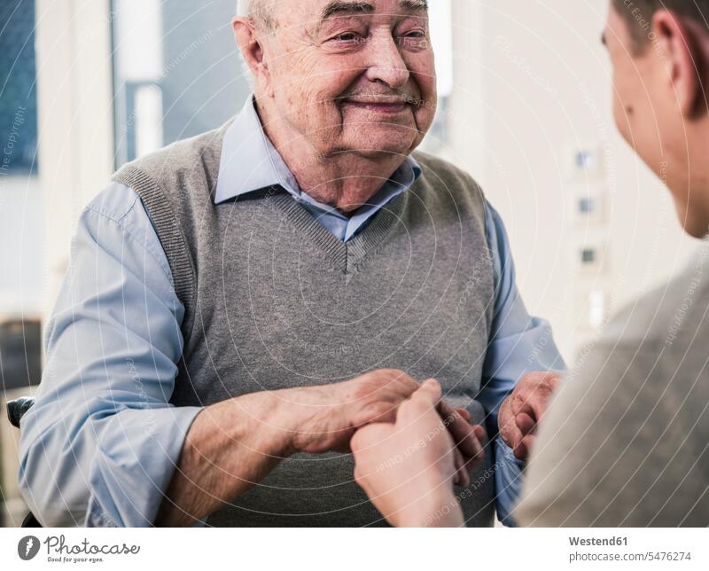 Älterer Mann lächelt jungen Mann an, der seine Hände hält lächeln Senior ältere Männer älterer Mann Senioren männlich Hand Erwachsener erwachsen Mensch Menschen
