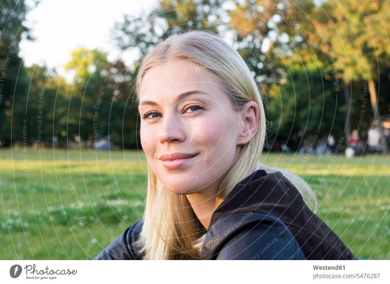 Porträt einer zufriedenen blonden Frau, die sich in einem Park entspannt Portrait Porträts Portraits weiblich Frauen Entspannung relaxen entspannen blonde Haare