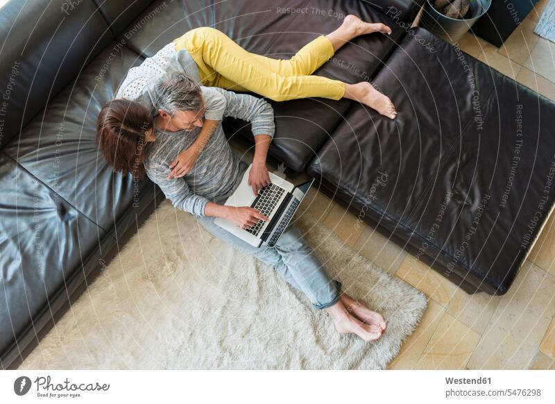 Ehepaar auf der Couch zu Hause, die sich einen Laptop teilen Teilen Sharing Zuhause daheim Notebook Laptops Notebooks Sofa Couches Liege Sofas Paar Pärchen