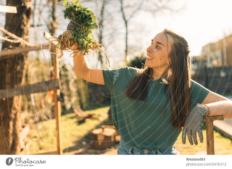 Stolze junge Frau hält Sellerie im Garten freuen Glück glücklich sein glücklichsein leidenschaftlich Leidenschaftlichkeit zufrieden stehend steht daheim