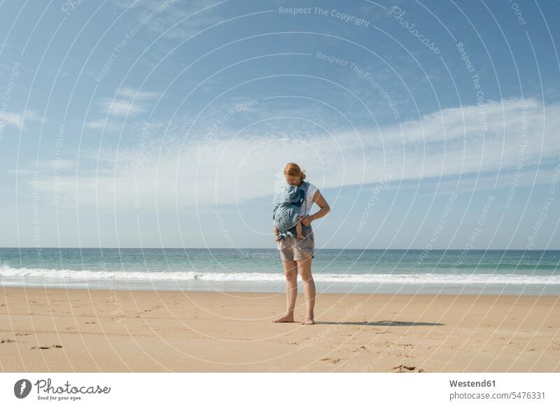 Spanien, Kap Trafalgar, Mutter mit Baby in Babytrage am Strand stehen stehend steht Ferien Urlaub Mami Mutti Mütter Mama Freizeit Muße Sandstrand Sandstrände