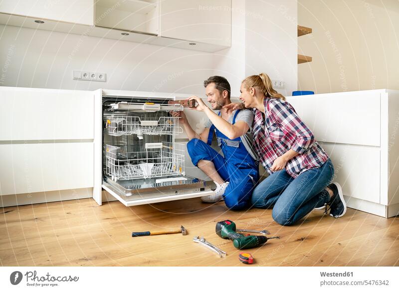 Ehepaar baut Geschirrspüler in ihre neue Einbauküche ein montieren befestigen Montage anpassen einbauen Küche Küchen Wasserwaage Geschirrspülmaschine