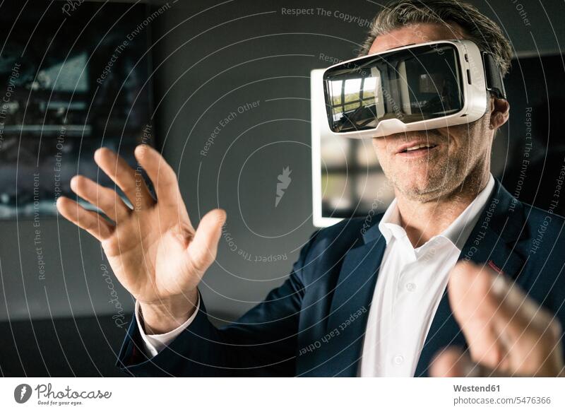 Reifer Geschäftsmann mit VR-Brille im Büro Office Büros Virtuelle Realität Virtuelle Realitaet Brillen Businessmann Businessmänner Geschäftsmänner Arbeitsplatz