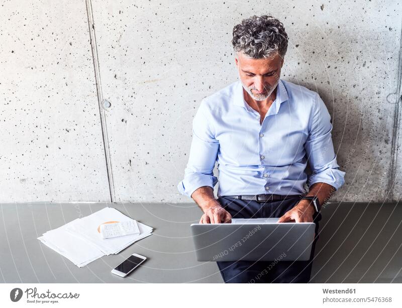 Ein reifer Geschäftsmann sitzt auf dem Boden und benutzt einen Laptop Businessmann Businessmänner Geschäftsmänner Böden Boeden Notebook Laptops Notebooks sitzen