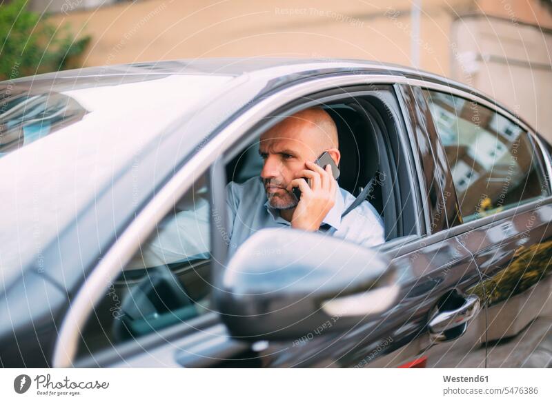 Geschäftsmann, der ein Fahrzeug fährt und ein Smartphone benutzt Leute Menschen People Person Personen Europäisch Kaukasier kaukasisch 1 Ein ein Mensch eine