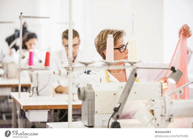 Näherinnen bei der Arbeit in einer Schneiderei Job Berufe Berufstätigkeit Beschäftigung Jobs Tische Textilien Gewebe Stoffe Textilfasern naehen sitzend sitzt