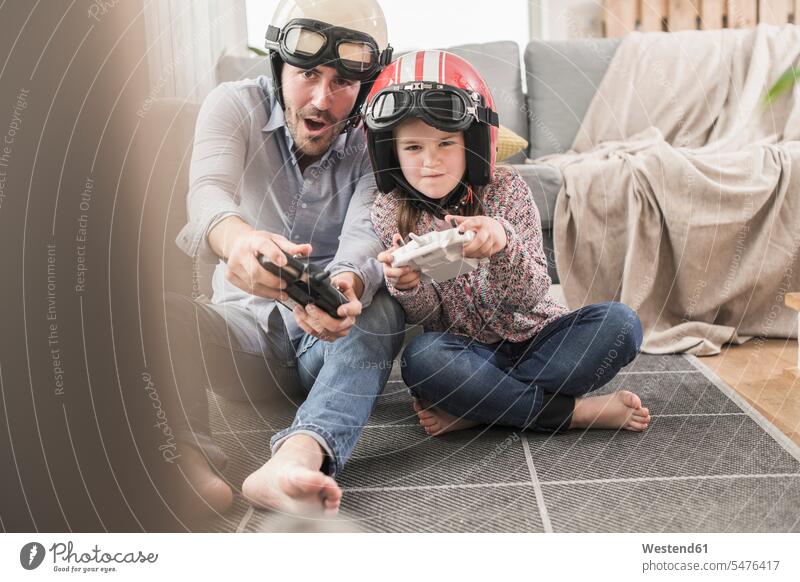 Junger Mann und kleines Mädchen tragen Biker-Helme, spielen Rennspiel mit Spielkonsolen Deutschland Quality Time Wohnen alleinerziehender Vater ein Elternteil