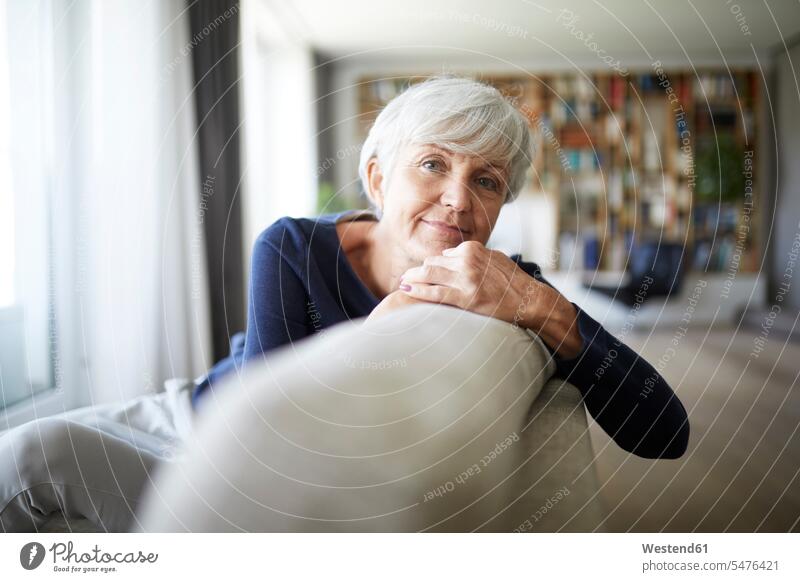 Kontemplierende ältere Frau, die auf dem Sofa sitzend entspannt Farbaufnahme Farbe Farbfoto Farbphoto Innenaufnahme Innenaufnahmen innen drinnen Tag