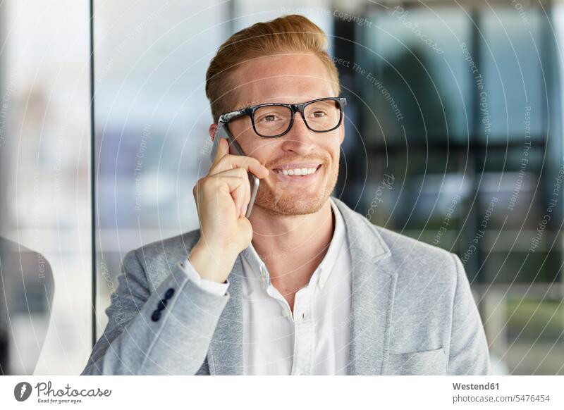 Porträt eines lächelnden rothaarigen Geschäftsmannes am Mobiltelefon Businessmann Businessmänner Geschäftsmänner Handy Handies Handys Mobiltelefone Brille