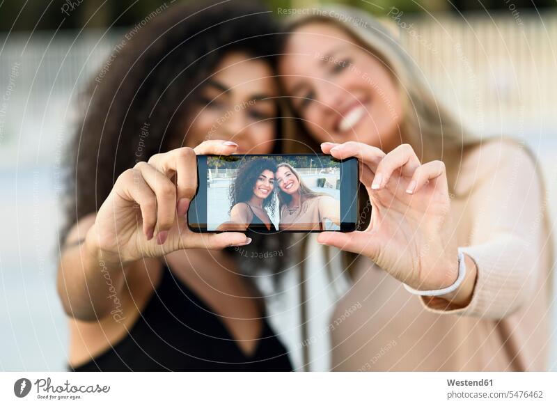 Zwei Freunde machen ein Selfie mit Handy, Nahaufnahme Smartphone iPhone Smartphones Selfies Mobiltelefon Handies Handys Mobiltelefone Freundschaft Kameradschaft