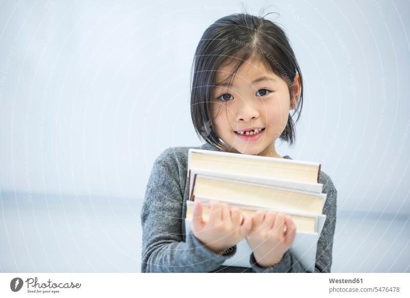Porträt eines lächelnden Schulmädchens, das Bücher in der Klasse trägt Buch Schülerin Schulklasse Schule Portrait tragen Schulkind Bildung Whiteboard