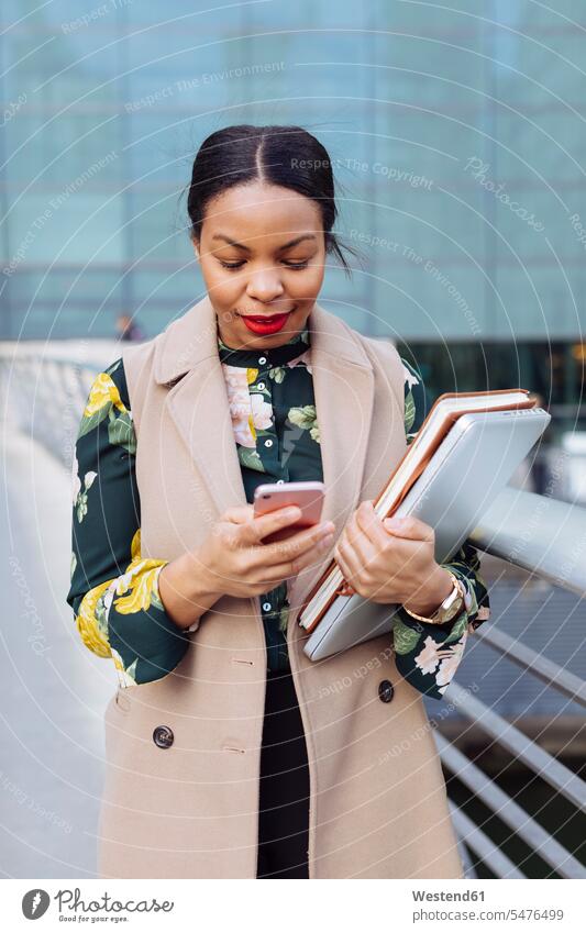 UK, London, modische Geschäftsfrau mit Blick auf das Handy Geschäftsfrauen Businesswomen Businessfrauen Businesswoman Smartphone iPhone Smartphones schauen