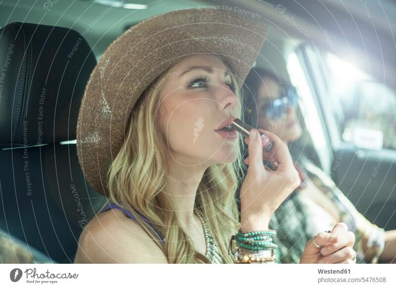 Schöne Frau trägt während einer Autofahrt Lippenstift im Auto auf Farbaufnahme Farbe Farbfoto Farbphoto Fahrzeuginnenraum Tag Tageslichtaufnahme