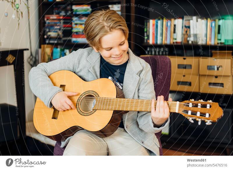 Junge spielt zu Hause Gitarre Instrument Instrumente Musikinstrumente Saiteninstrumente Gitarren Akustikgitarren Klassische Gitarre Klassische Gitarren sitzend