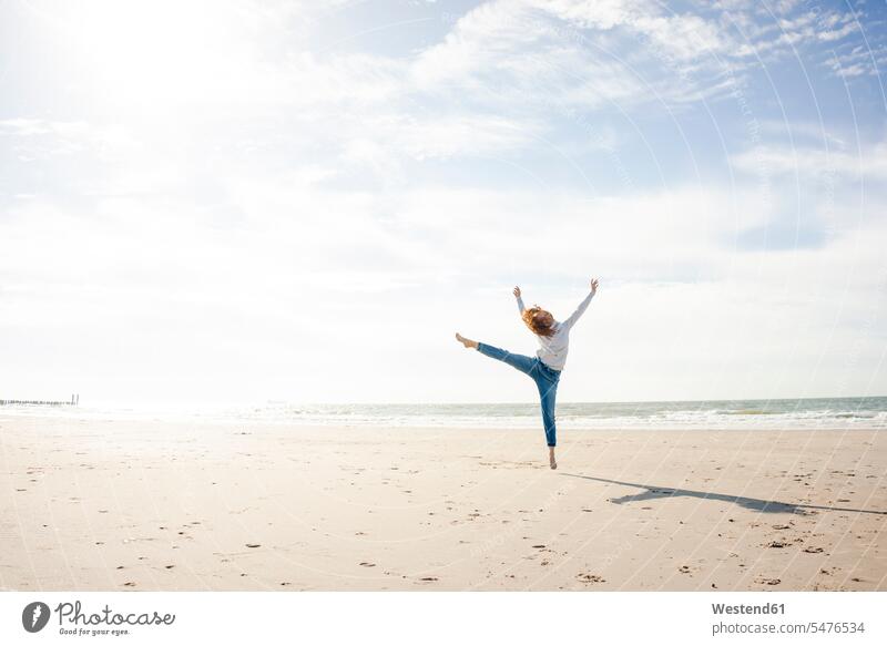 Glückliche Frau hat Spaß am Strand, springt in die Luft Beach Straende Strände Beaches tanzen tanzend weiblich Frauen springen hüpfen glücklich glücklich sein