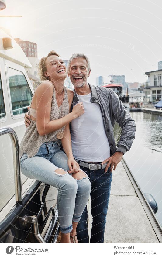 Lachender älterer Mann und junge Frau stehen auf dem Steg neben der Yacht lachen Stege Anlegestelle Jacht Yachten Jachten Paar Pärchen Paare Partnerschaft
