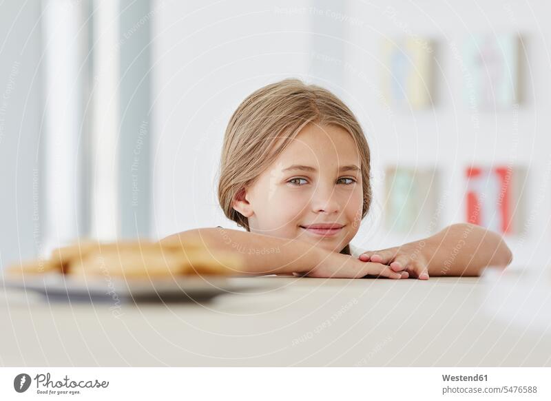 Porträt eines süßen Mädchens zu Hause mit Teller auf dem Tisch Koepfe Köpfe Gesichter Tische zufrieden daheim Wuensche wuenschen Wünsche wünschen Essen