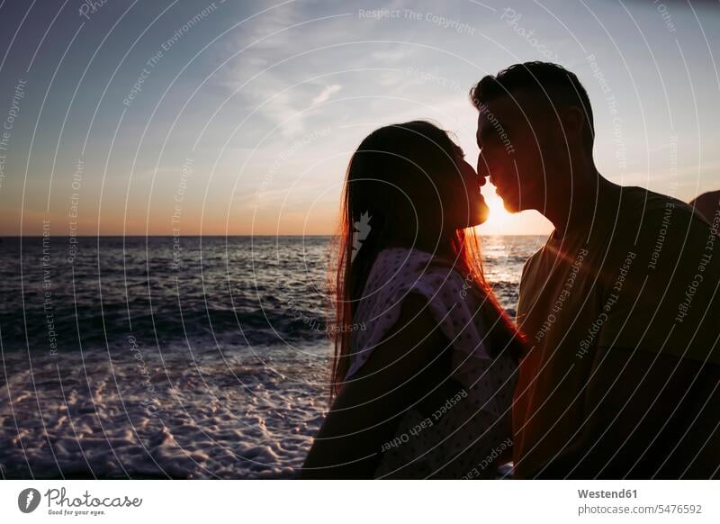 Junges Paar küsst sich bei Sonnenuntergang am Strand Handtuecher Handtücher abends geniessen Genuss gefühlvoll Emotionen Empfindung Empfindungen fühlen Gefühl