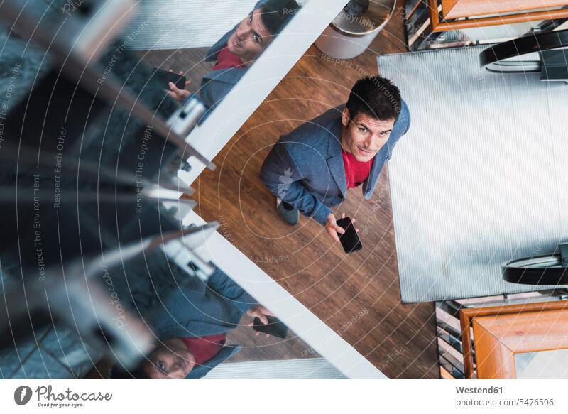 Geschäftsmann in der Lobby eines modernen Gebäudes, mit Smartphone benutzen benützen unterwegs auf Achse in Bewegung iPhone Smartphones arbeiten Arbeit
