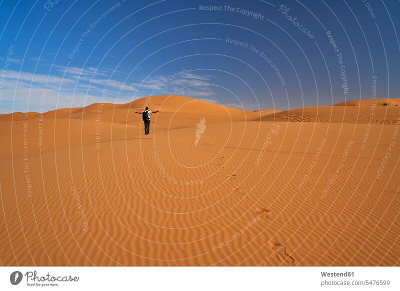 Marokko, Rückenansicht eines Mannes mit Rucksack, der auf einer Wüstendüne steht Männer männlich Rucksäcke stehen stehend Wüstendünen Wuestenduene Wuestenduenen