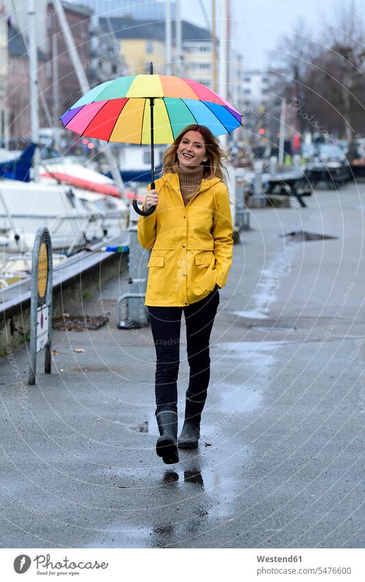 Dänemark, Kopenhagen, glückliche Frau mit buntem Regenschirm schlendert am Stadthafen farbig mehrfarbig staedtisch städtisch Glück glücklich sein glücklichsein