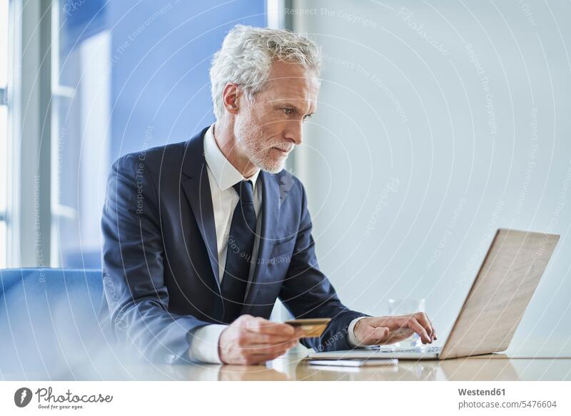 Geschäftsmann mit Kreditkarte und Laptop am Schreibtisch im Büro Job Berufe Berufstätigkeit Beschäftigung Jobs geschäftlich Geschäftsleben Geschäftswelt