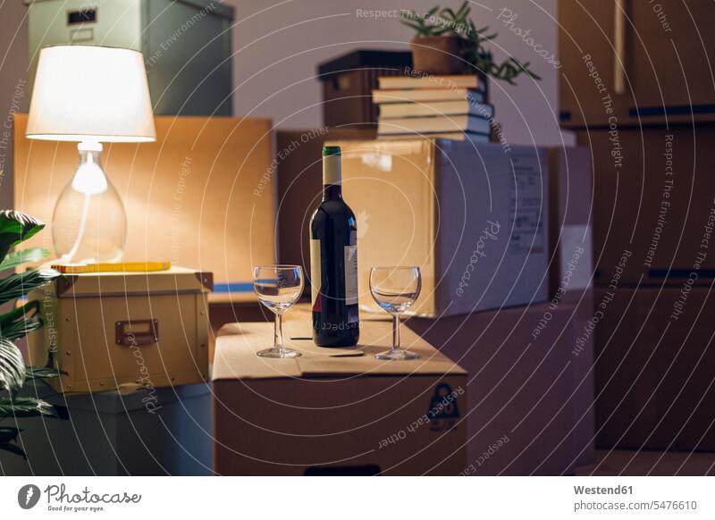 Weinflasche und Gläser auf Pappkarton in einem leeren Raum in einem neuen Zuhause umziehen drinnen Innenaufnahmen abwesend menschenleer selbständig