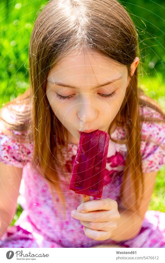 Porträt eines Mädchens, das im Garten Eis am Stiel isst weiblich Portrait Porträts Portraits Gärten Gaerten Stieleis Popsicle Popsicles essen essend Kind Kinder