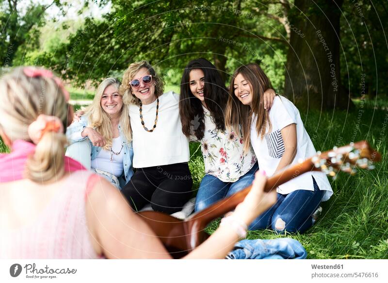 Gruppe von Frauen mit Gitarre haben Spaß bei einem Picknick im Park Spass Späße spassig Spässe spaßig weiblich picknicken Parkanlagen Parks Freundinnen Gitarren