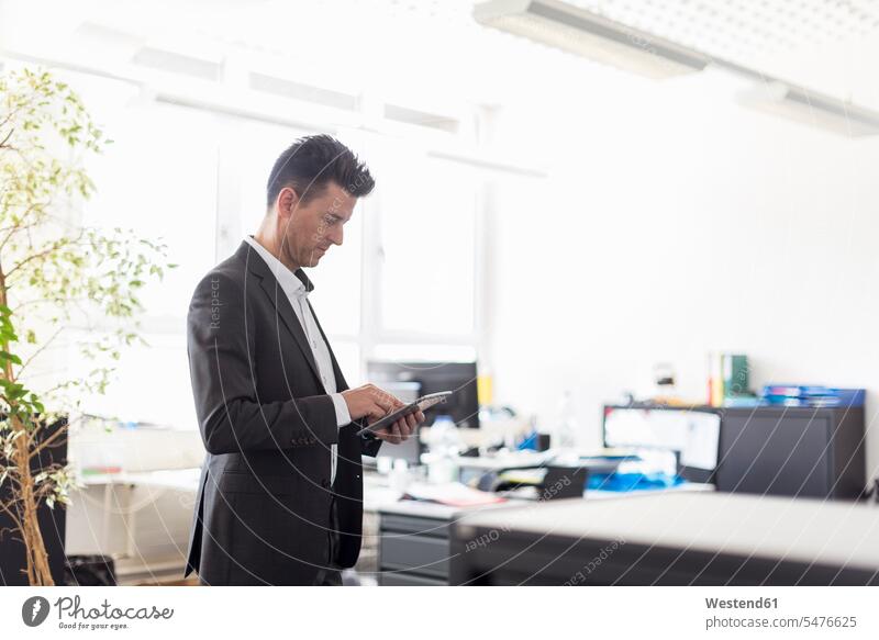 Erfolgreicher Geschäftsmann im Amt stehend, mit digitalem Tablet Büro Office Büros Tablet Computer Tablet-PC Tablet PC iPad Tablet-Computer steht benutzen