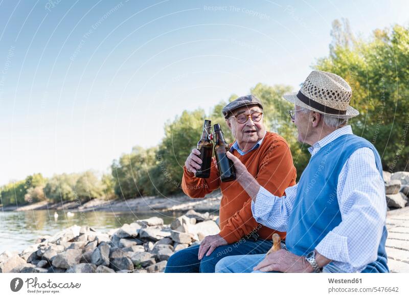 Alte Freunde sitzen am Flussufer und trinken Bier jung geblieben junggeblieben jugendlich jugendlichkeit Lebensqualität Pause Pause machen genießen geniessen
