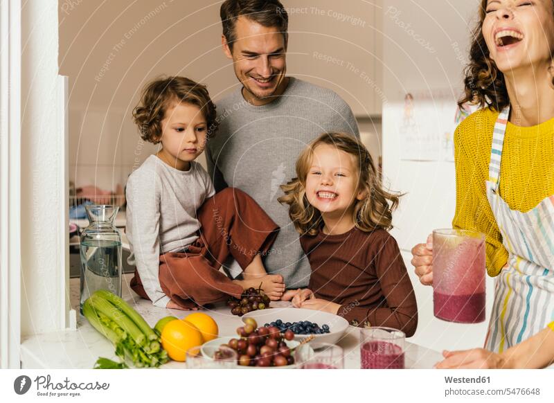 Glückliche Familie macht einen Smoothie in der Küche Hausfrauen Gläser Trinkglas Trinkgläser freuen Frohsinn Fröhlichkeit Heiterkeit behüten behütet geborgen