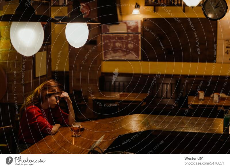 Traurige Frau mit Bierglas auf Bartheke im Restaurant sitzend Farbaufnahme Farbe Farbfoto Farbphoto Spanien Millennials junge Erwachsene erwachsen Mensch